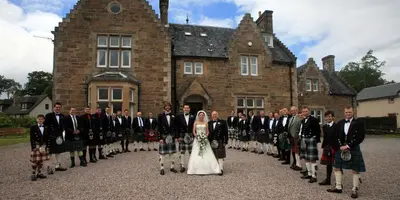 a group of people in kilts standing in front of a building at Rudha-na-Craige in Inveraray