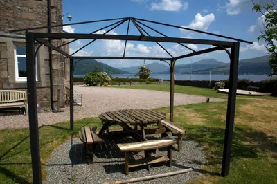a wooden picnic table and benches in a pavilion at Rudha-na-Craige in Inveraray