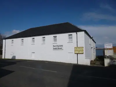 a white building with a sign on the side of it at Port Charlotte Youth Hostel in Port Charlotte