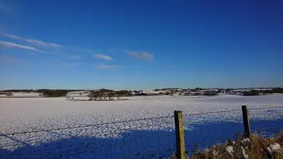a fence in front of a snow covered field at The Haven Cottage in Slamannan