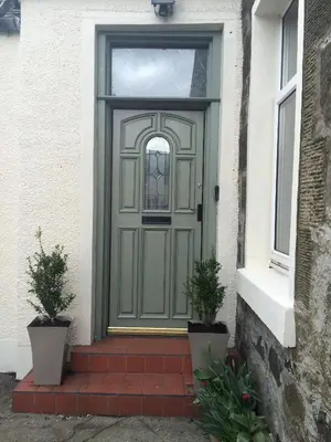 a green door on a house with two potted plants at The Haven Cottage in Slamannan