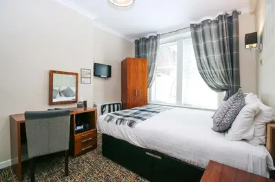 a bedroom with a bed and a window and a desk at Kelvingrove Hotel - Sauchiehall St in Glasgow