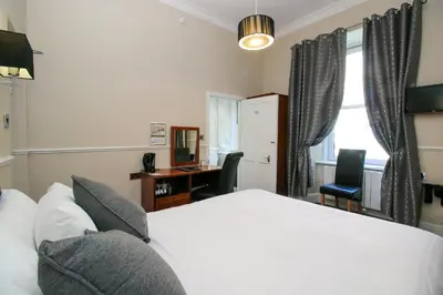 a bedroom with a bed and a desk and a window at Kelvingrove Hotel - Sauchiehall St in Glasgow