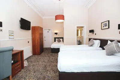 a hotel room with two beds and a flat screen tv at Kelvingrove Hotel - Sauchiehall St in Glasgow