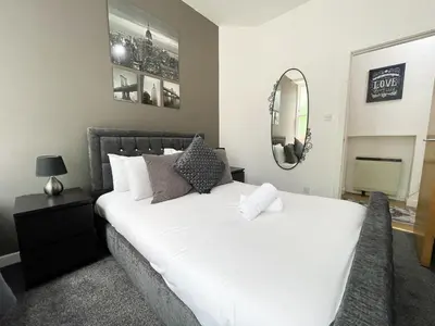 a bedroom with a white bed and a mirror at Exquisite 2BR Flat near Central Train Station in Glasgow