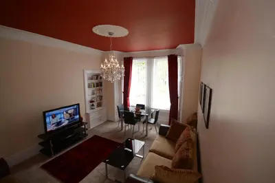 a living room with a couch and a tv and a table at Townhead Apartments Gallery View in Paisley