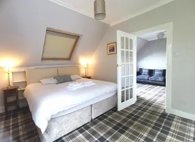 a bedroom with a white bed and a couch at The Knowe Guest House in Callander