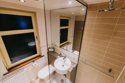 a bathroom with a sink and a toilet and a mirror at Lynnhurst Hotel in Johnstone