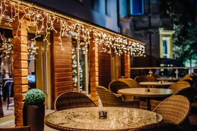 a restaurant with tables and chairs and lights at Lynnhurst Hotel in Johnstone