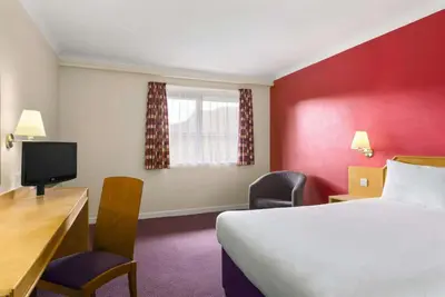 a room with a bed and a desk and a tv at Days Inn Hamilton in Hamilton