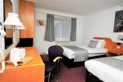 a hotel room with two beds and a desk at Days Inn Hamilton in Hamilton