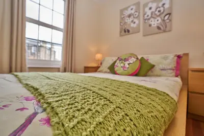a bedroom with a green blanket on a bed at Edinburgh Pearl Apartments - Haymarket Residence in Edinburgh