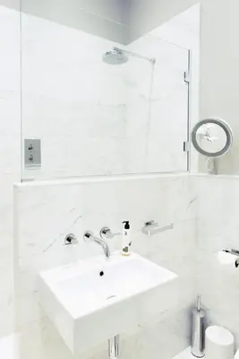 a white bathroom with a sink and a mirror at Ramsay Gardens - Grand 4-Bedroom Apartment Next To Castle in Edinburgh