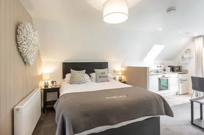 a bedroom with a large bed and a kitchen at Loch Lomond Luxury Lodges in Drymen