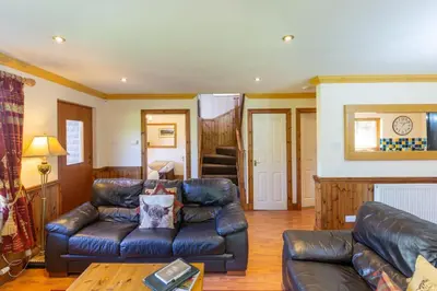 a living room with a leather couch and a table at Loch Lomond Luxury Lodges in Drymen
