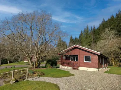 a small cabin with a porch in a park at Ruskin Lodges Argyll, by Puck's Glen, Rashfield near Dunoon in Dunoon