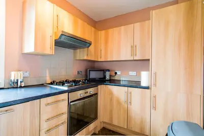 a kitchen with wooden cabinets and a stove top oven at Montgomery Apartments - Stevensons in Edinburgh