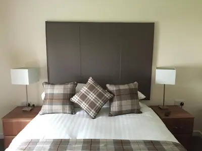 a bedroom with a bed with pillows and two lamps at Bruce's Cottage in Stirling