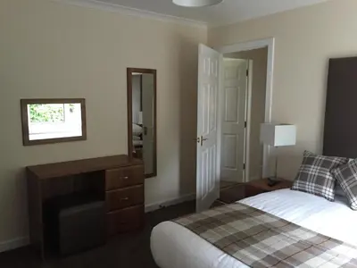a bedroom with a bed and a dresser and a mirror at Bruce's Cottage in Stirling