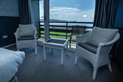 two chairs and a table in a room with a balcony at Loch Melfort Hotel in Ardfern