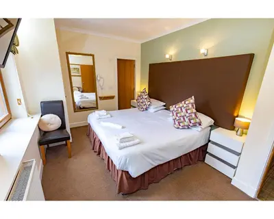 a hotel room with a large bed and a mirror at The Crown in Callander