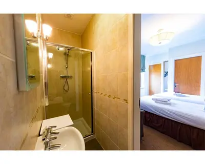 a bathroom with a sink and a shower and a bed at The Crown in Callander