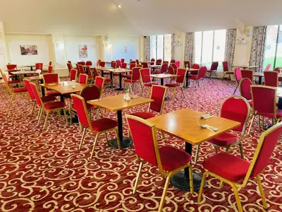 a dining room with tables and red chairs at Adamton Country House Hotel in Prestwick