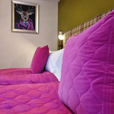 a bedroom with a pink bed and a picture of a deer at Rose Villa in Oban