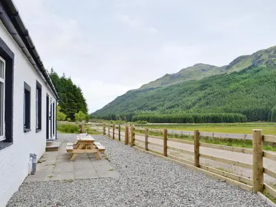 a picnic table outside of a building with mountains in the background at Corrie Massan in Benmore