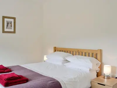 a bed with white sheets and red towels on it at Corrie Massan in Benmore
