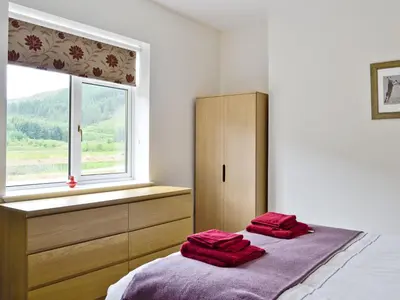 two red towels are sitting on a bed in a bedroom at Corrie Massan in Benmore