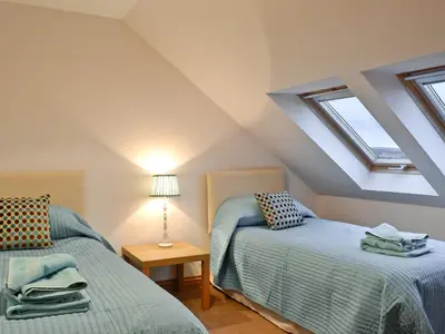a attic bedroom with two beds and a table at Bruichladdich in Rothesay