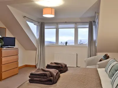 a bedroom with a bed with a large window at Bruichladdich in Rothesay