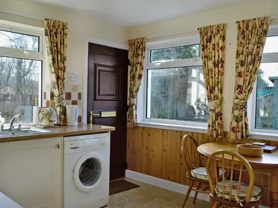 a kitchen with a washing machine and a table with chairs at Baravullin in Benderloch