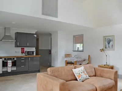a living room with a couch and a kitchen at Geordies Byre in Mill of Fortune