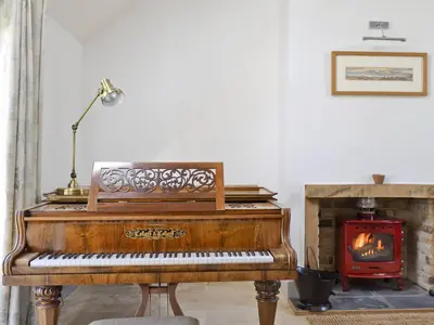 a piano in a living room with a fireplace at Ben Hennie in Mill of Fortune