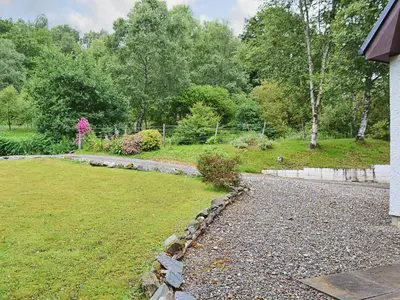 a garden with a stone path next to a house at Bethany Cottage in Aberfoyle