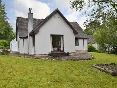 a white house with a grass yard at Bethany Cottage in Aberfoyle