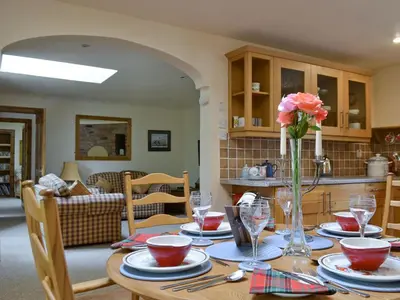 a dining room table with a vase of flowers on it at Old Stones in Glendevon