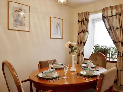 a dining room with a wooden table and chairs at Ross Cottage in Cairneyhill