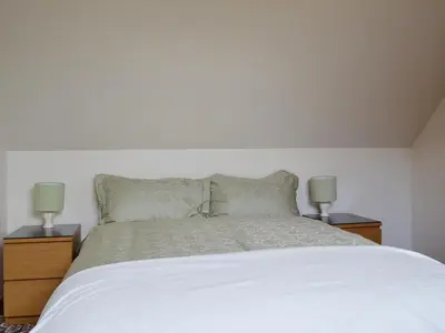 a bedroom with a white bed with two lamps at Ross Cottage in Cairneyhill
