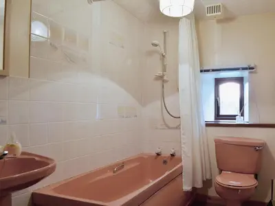 a bathroom with a pink tub and a sink at Ross Cottage in Cairneyhill