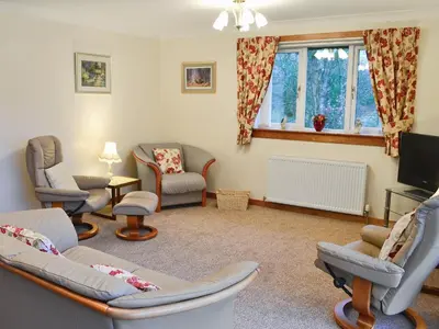 a living room with couches and chairs and a tv at Eilean Donan in Kirknewton