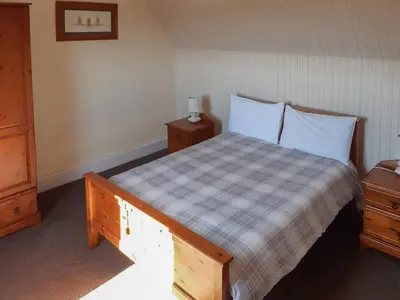 a bedroom with a bed with a checkered bedspread and two night stands at Old Barn Farmhouse - Cc in Uplawmoor