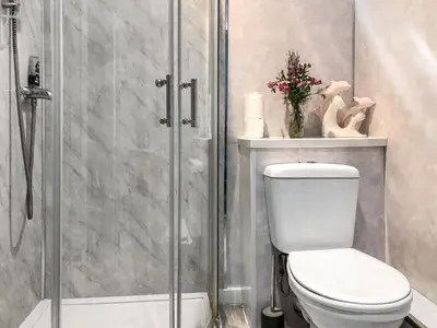 a bathroom with a toilet and a glass shower at Old Barn Farm Cottage - Cc in Uplawmoor