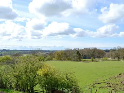 a green field with trees and clouds in the sky at Old Barn Farm Cottage - Cc in Uplawmoor