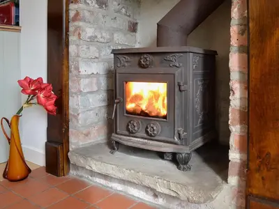 a wood stove in a room with a fireplace at Wee Dug Hoose in Glenluce