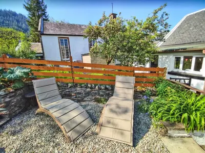 two chairs sitting in front of a fence at Fern Cottage in Ardentinny