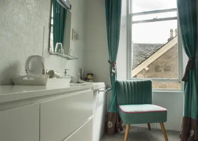 a bathroom with a sink and a chair and a window at The Ben Sheann in Strathyre