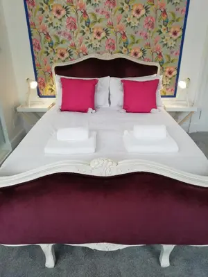 a large white bed with two pink pillows at The Ben Sheann in Strathyre
